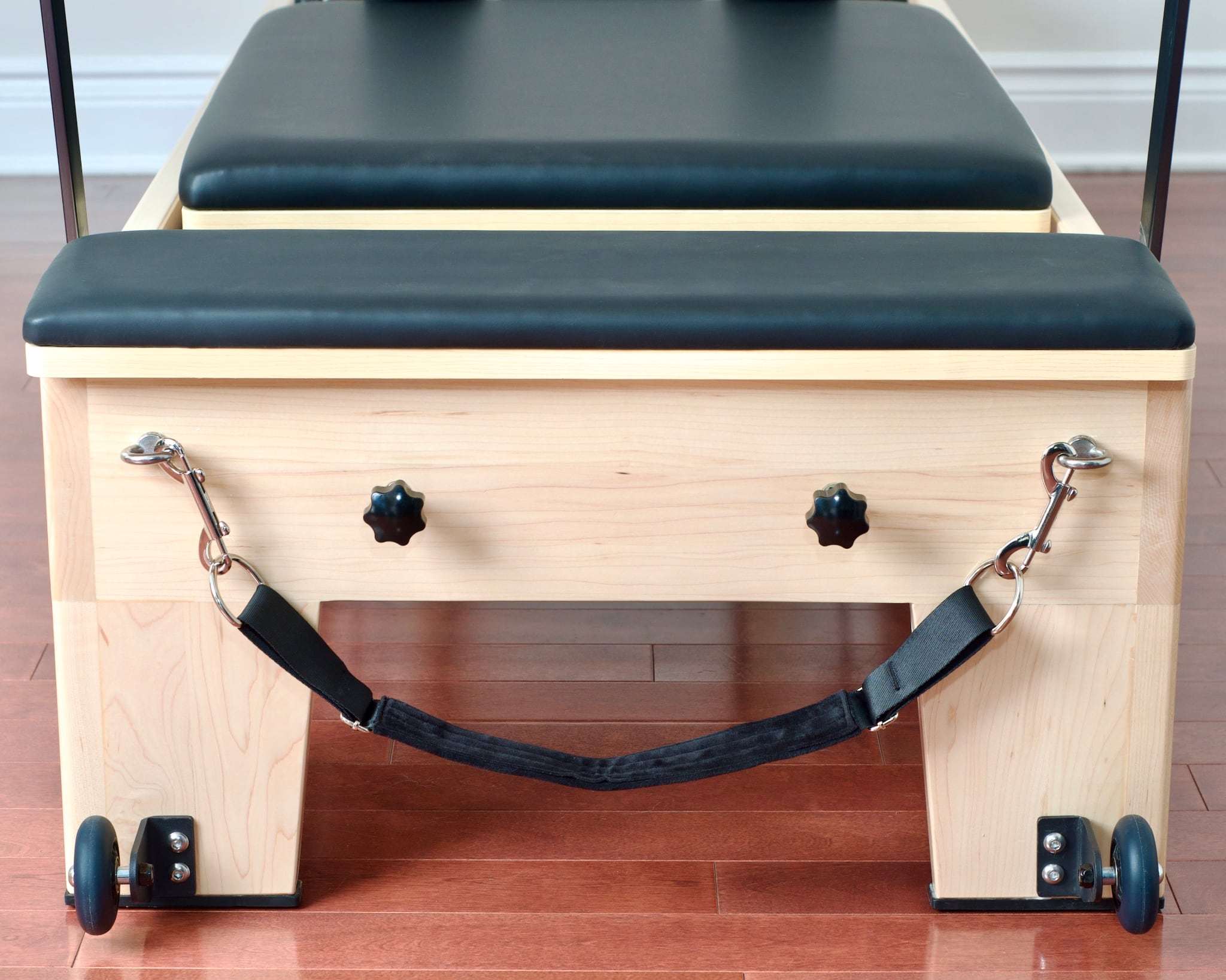 Front view of Maple Elite Studio Reformer With Tower showing the platform extender, mat converter, and foot strap.