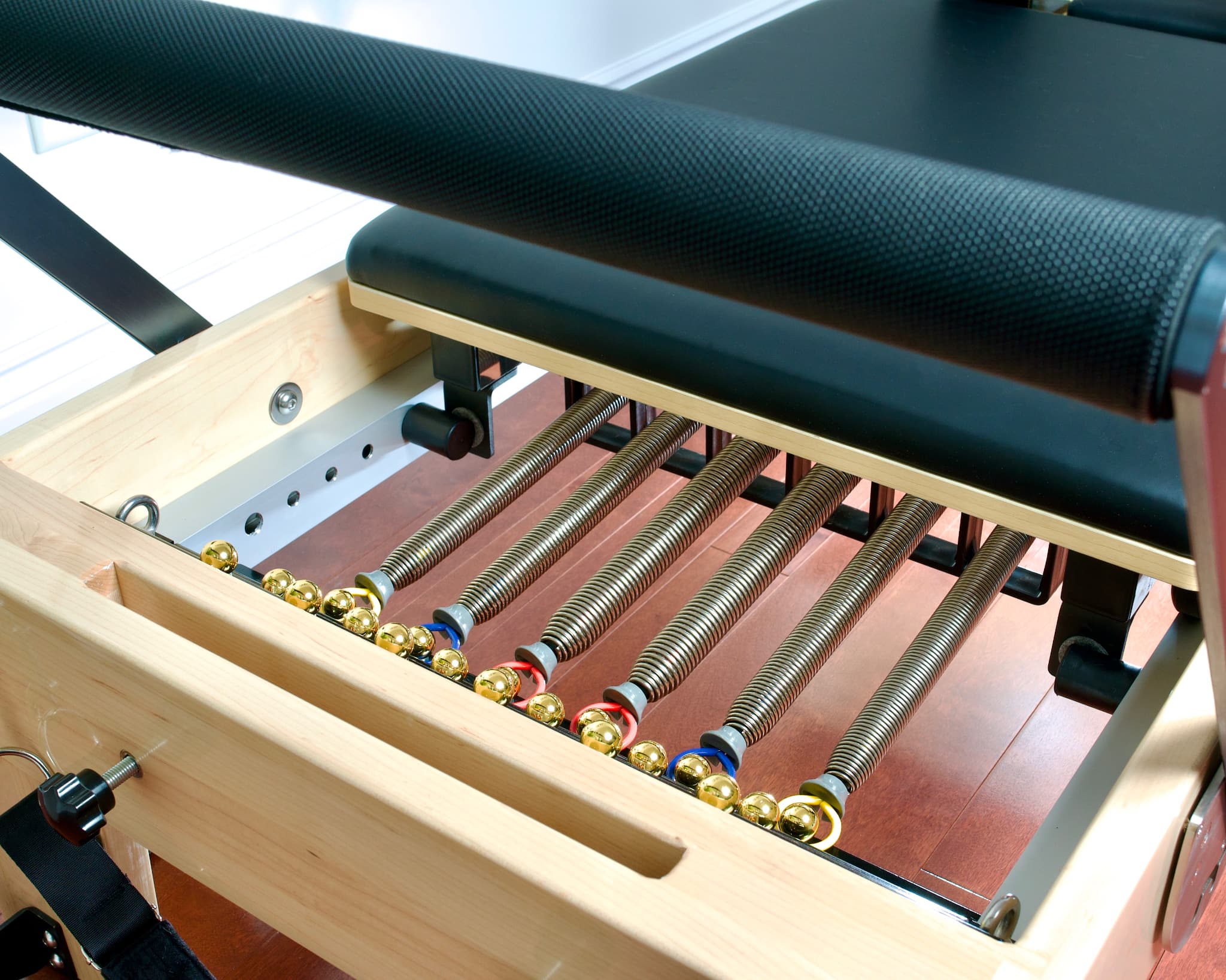 Angled view of the spring system and carriage stoppers for the Maple Elite Studio Reformer With Tower.