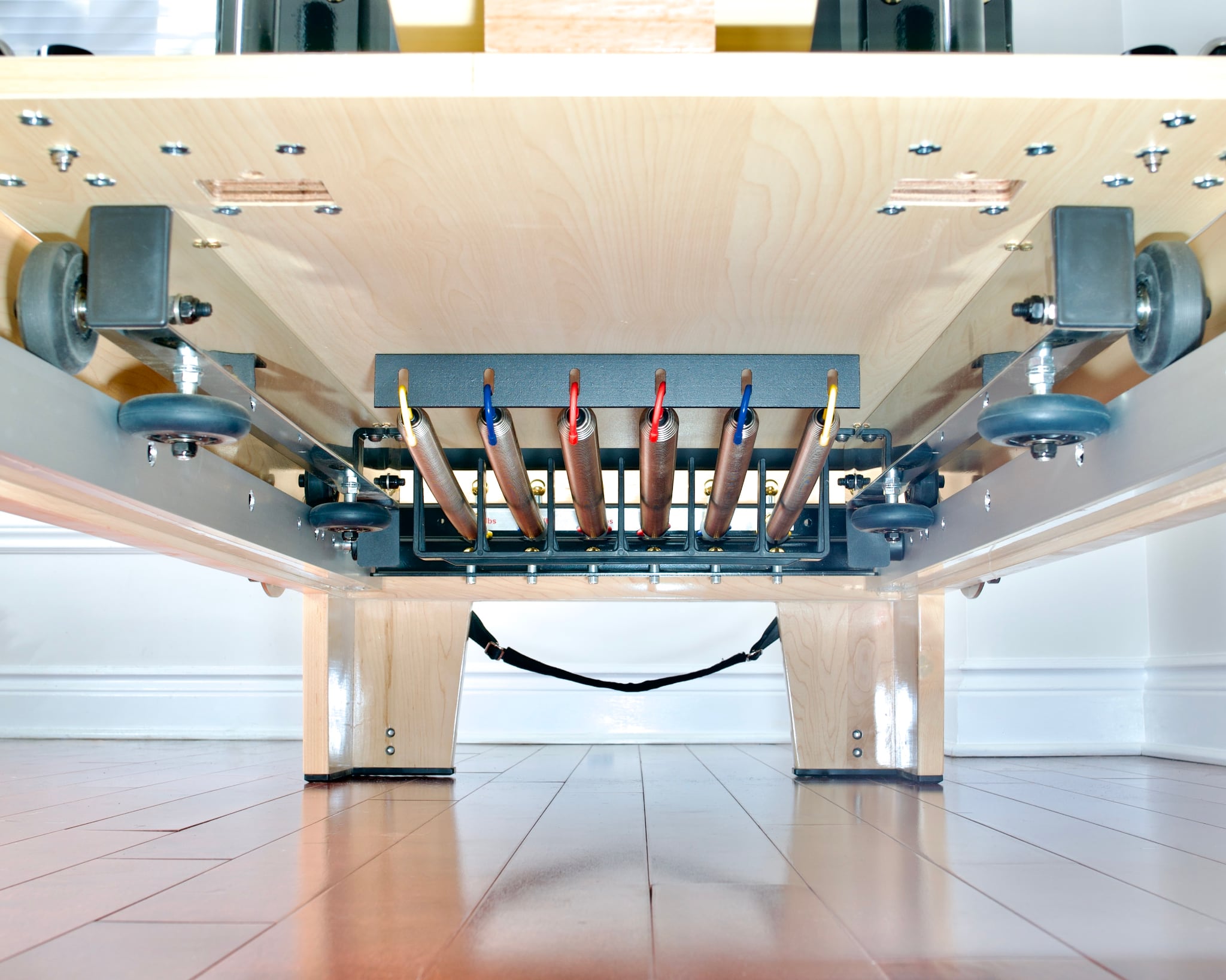 Underside of the Maple Elite Studio Reformer With Tower.  Focus on the rail and spring system.